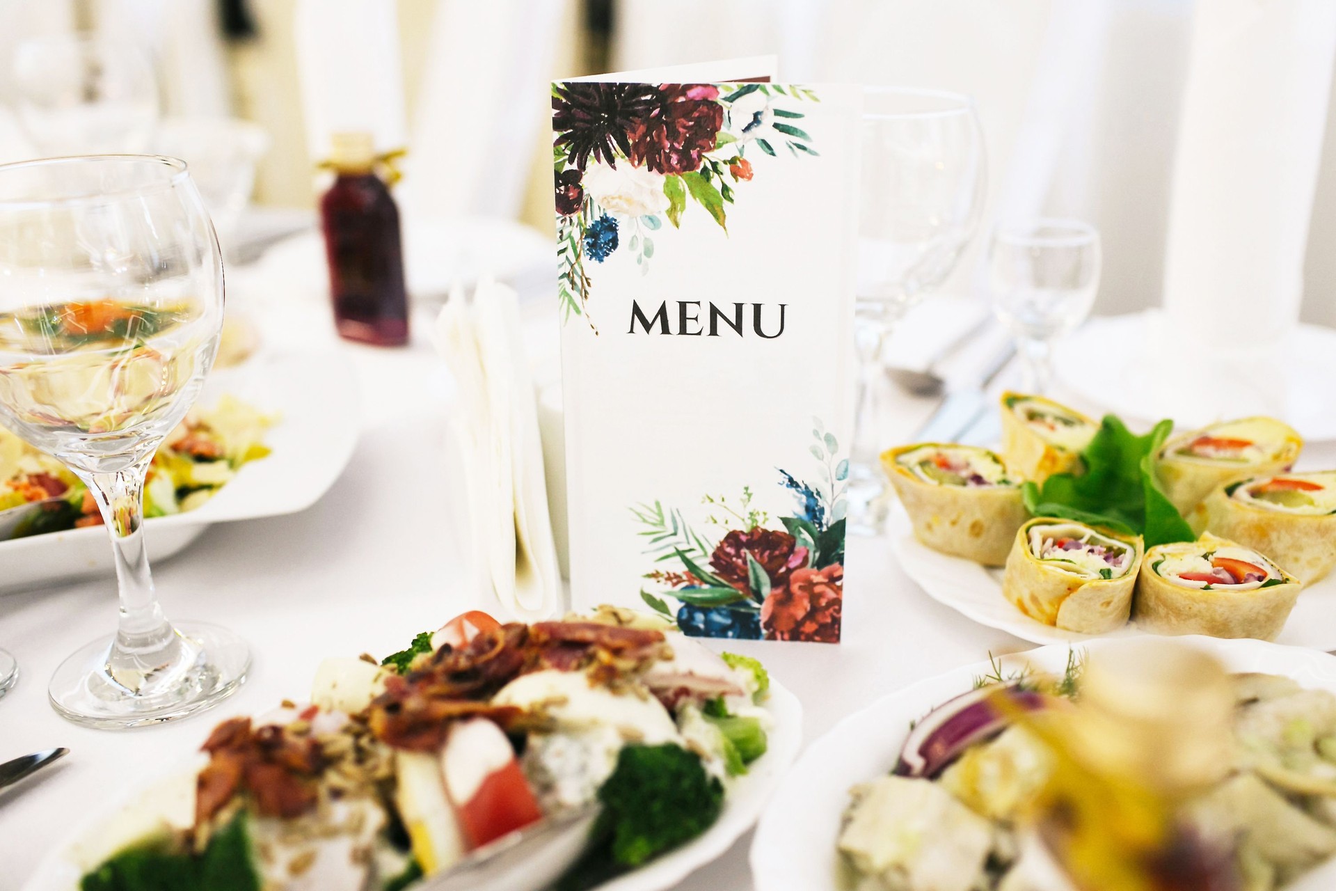 Elegant menu card on a dinner table at a festive celebration. Dining setup with gourmet food, flowers, and cutlery.